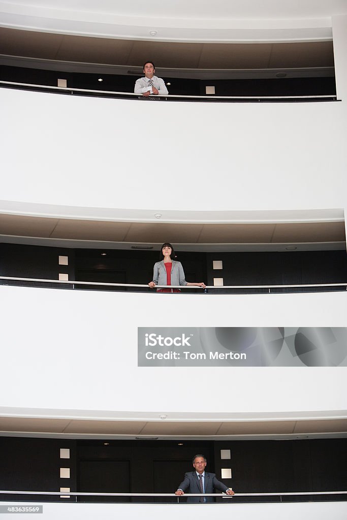 Business people standing at balcony in atrium  20-24 Years Stock Photo