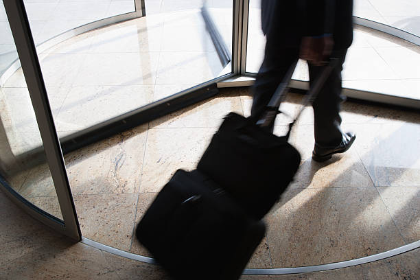 Businessman with suitcase using revolving door  Traveled stock pictures, royalty-free photos & images