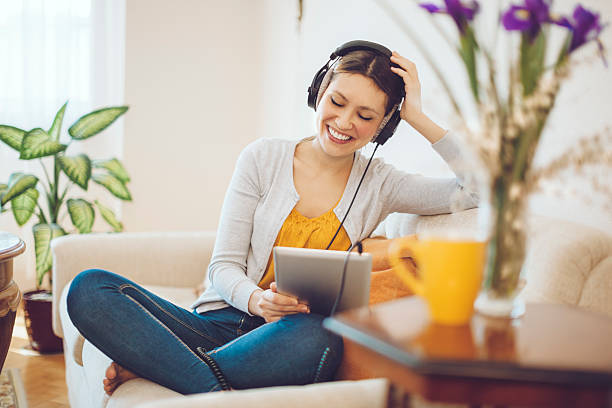 sonriente mujer escuchando música en su hogar - living room elegance women long hair fotografías e imágenes de stock