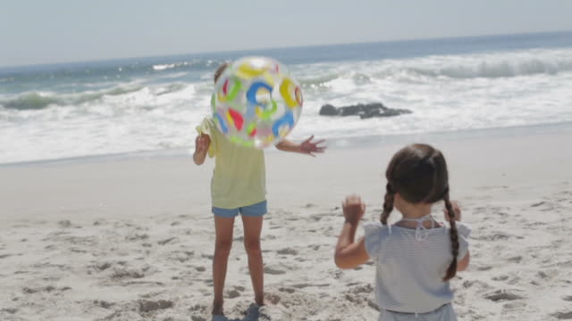 Girls throwing ball on beach