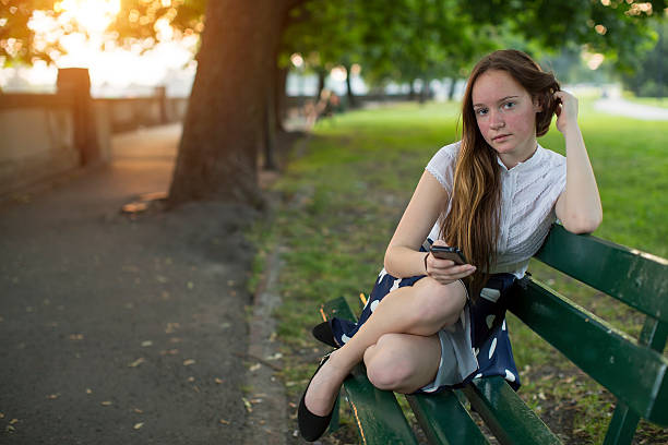 istock Young girl sits with a smartphone on a bench. 483645146