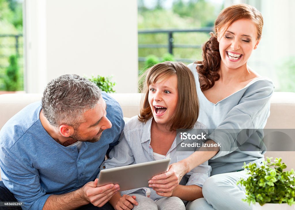 Happy family with digital tablet Playful family fighting for a digital tablet.  Digital Tablet Stock Photo