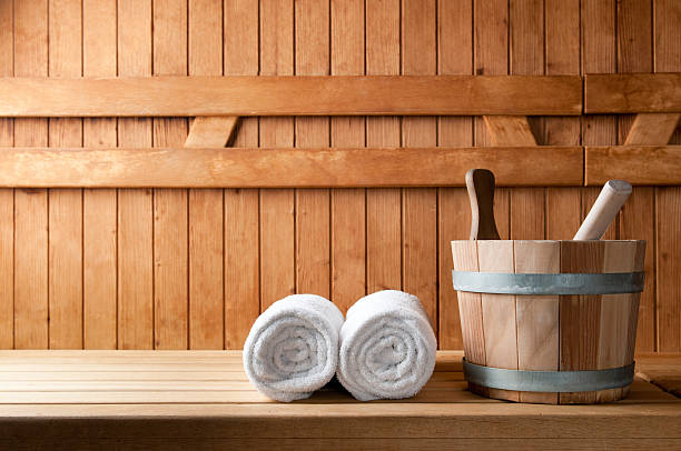 Wooden bucket and white rolled towels in a sauna Detail of bucket and white towels in a sauna. sauna stock pictures, royalty-free photos & images