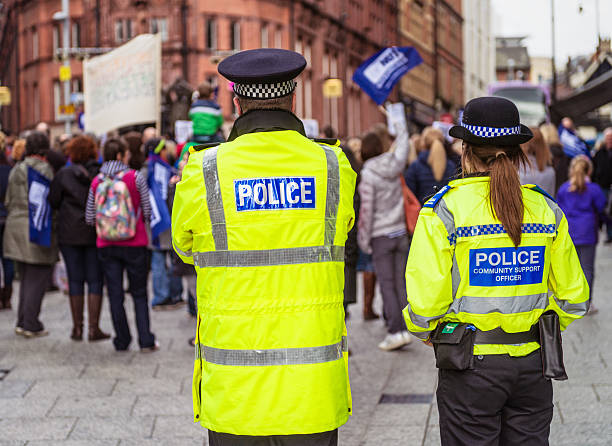 Police Officers at a peaceful demonstration Nottingham, UK - March 26, 2014: Two police officers watching a peaceful demonstration by trade union members on the day of a national strike by teachers, in protest of Department of Education policies. strike protest action stock pictures, royalty-free photos & images