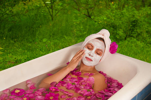beautiful woman enjoying floral bath beautiful woman enjoying bath with rose petals outdoors beauty and beast rose stock pictures, royalty-free photos & images