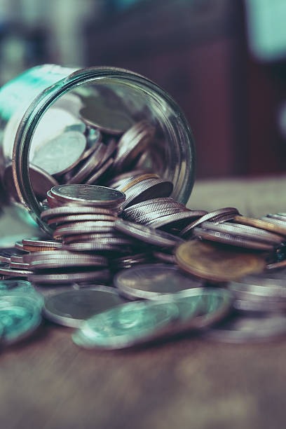Coins spilling out of a glass bottle