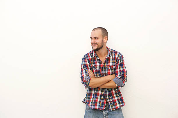 Smiling young man in plaid shirt standing with arms crossed