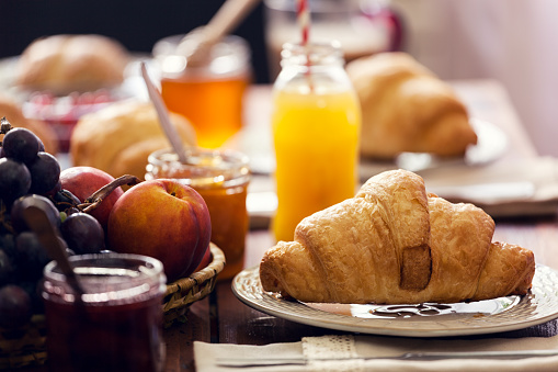 A breakfast of coffee and croissants with juice. This image depicts a delightful and typical breakfast combination featuring coffee, croissants, and juice, creating a cozy and delicious atmosphere to start the day.