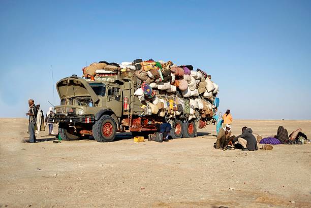 African immigrant Mondou, Chad - December 8, 2012: The picture was took in the desert of Chad during a morning time, we can see a group of immigrant traveling to another country, they are close to a border, when the truck full of goods break down. December 2012 unicef stock pictures, royalty-free photos & images