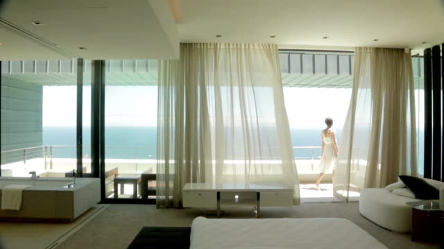 View from bedroom of woman on luxury balcony overlooking ocean