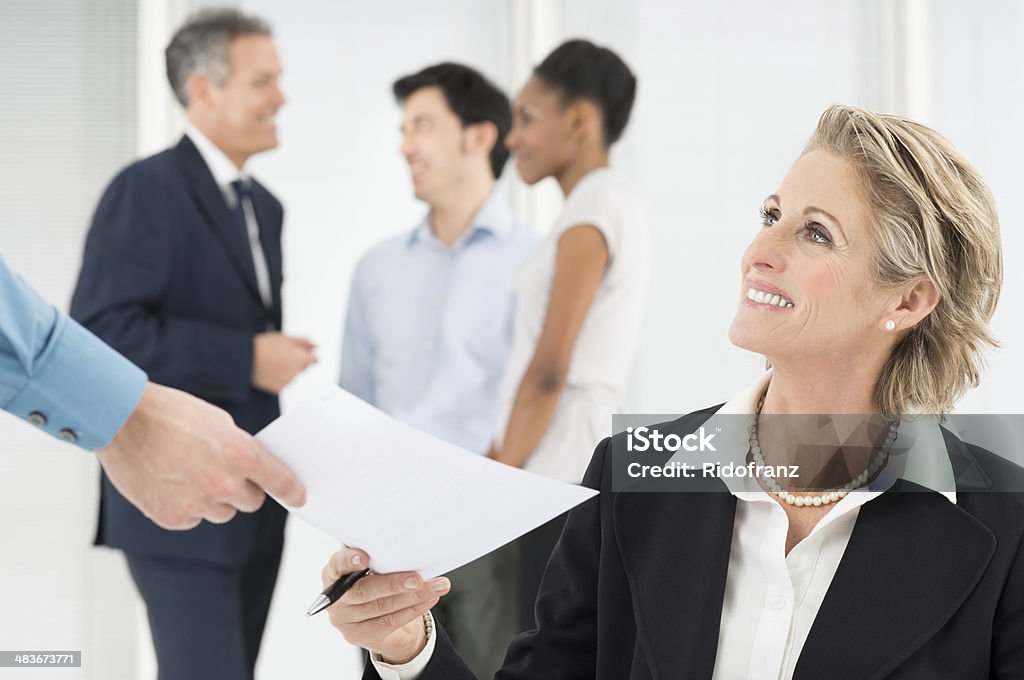 Happy Businesswoman Holding Document Portrait Of Smiling Mature Businessman Giving Document To Colleague Business Meeting Stock Photo