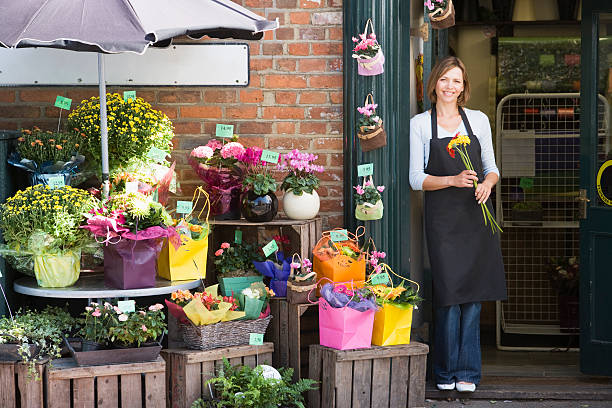 Woman working at flower shop smiling holding bunch of flowers