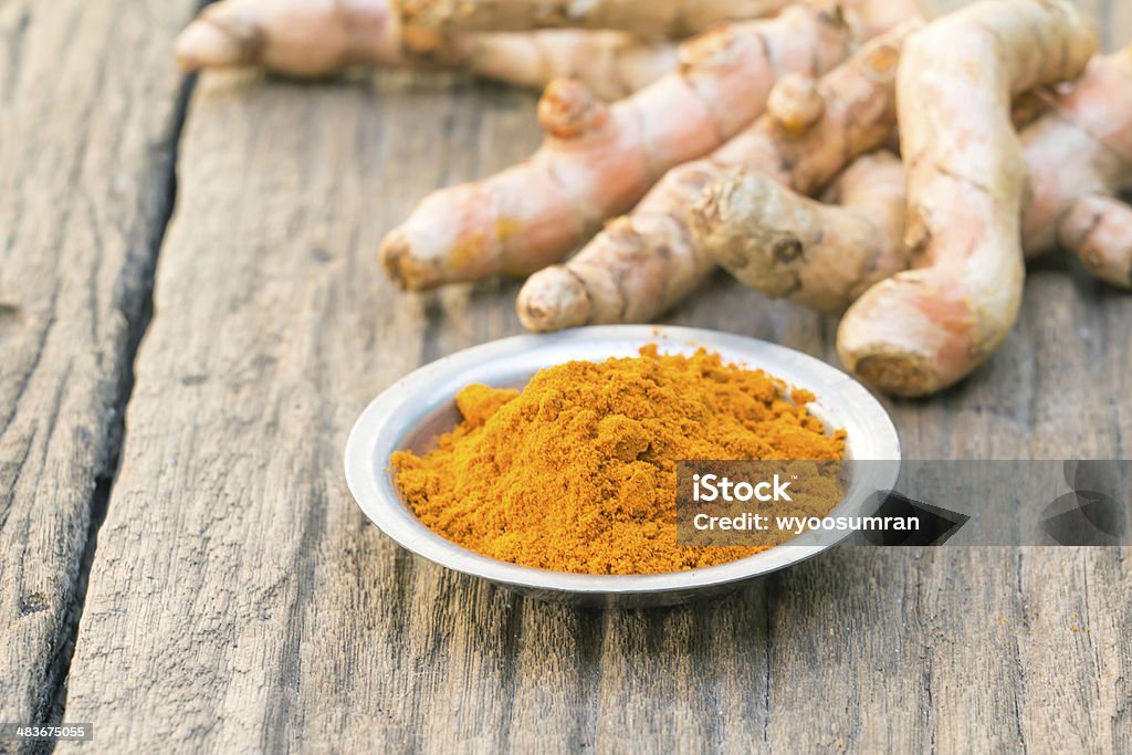 Fresh turmeric Fresh turmeric root, and turmeric powder on wood background Close-up Stock Photo