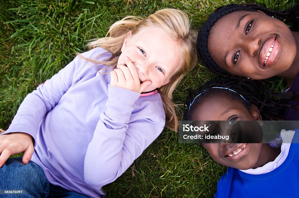 Tres niñas feliz Riendo en el césped - Foto de stock de 12-13 años libre de derechos