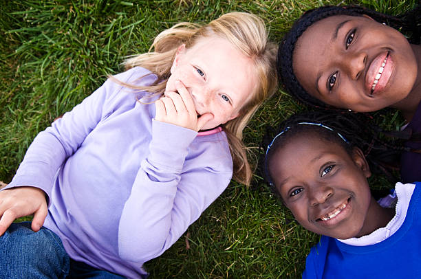 istock Three Happy Girls Laughing in the Grass 483675097