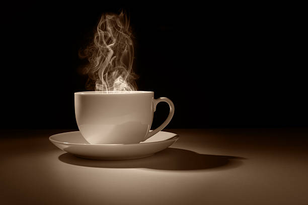 Hot coffee or tea in a cup silhouette against a dark background