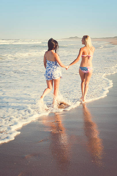 two young attractive girls walking on beach stock photo