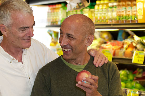 Senior Gay Male Couple Smiling and Shopping for Groceries stock photo