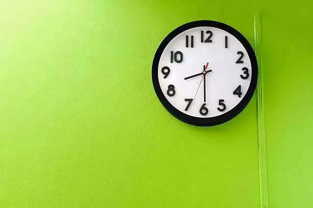 Clock showing 8:30 o'clock on a green wall