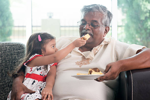 istock Granddaughter feeding grandfather cake 483683968