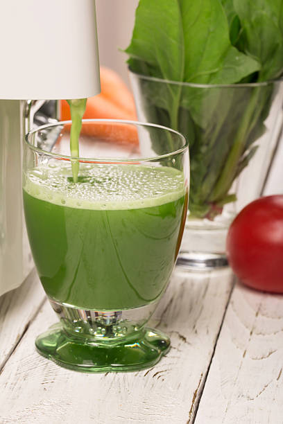 Spinach juice from juicers pouring into a glass stock photo