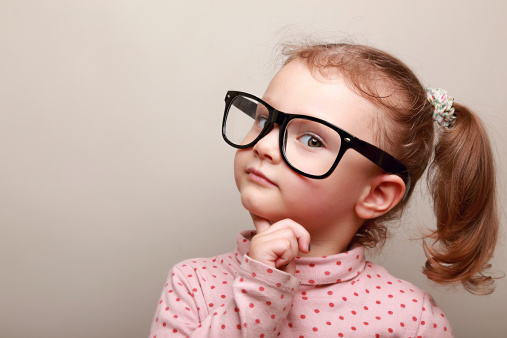 Smart dreaming kid girl in glasses looking. Closeup portrait