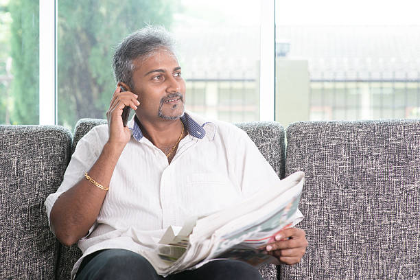 istock Indian man reading newspaper and calling phone 483686940