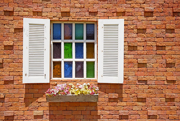 White window with flower pots on the brick wall background.White window with flower pots on the brick wall background.