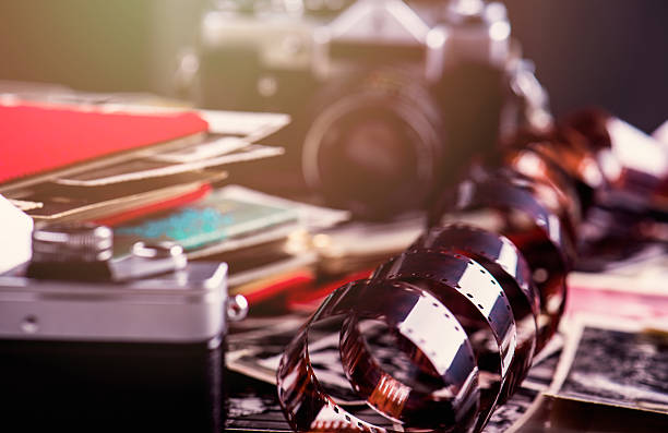 35mm film 35mm film surrounded with cameras, pictures, albums. Shallow DOF. Little flare. old black leather photo album stock pictures, royalty-free photos & images