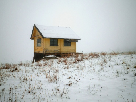 A tiny wooden cottage covered with snow in Siberia.