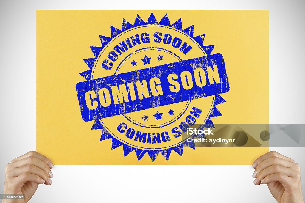 Coming Soon sign Woman's hand holding Coming Soon sign. Advertisement Stock Photo