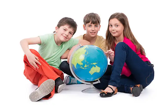 Two boys and girl looking on globe map travel locations for a summer vacation. Isolated on white image.