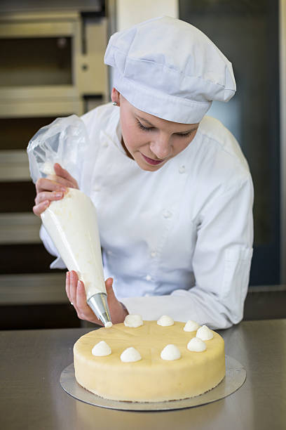 istock Baker prepares cake in bakehouse with whipped cream 483692877