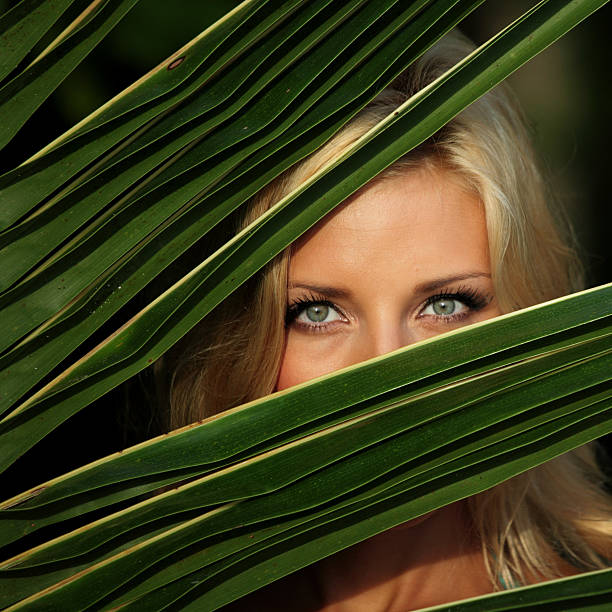 A smiling red-haired woman enjoys nature, surrounded by ferns and golden sunlight, embodying pure joy and relaxation.