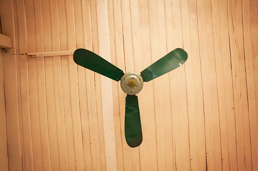 Green big old ceiling fan. Old building with wooden ceiling in Laos.