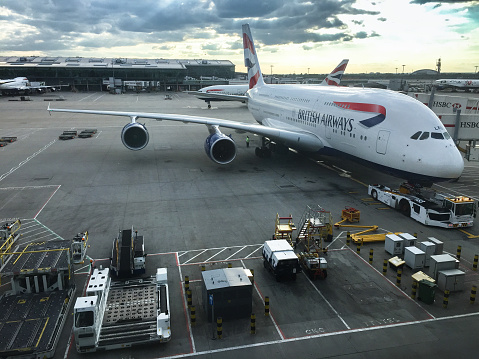 London, UK - June 15, 2015: An Airbus A380, the world's largest passenger aircraft sits at the terminal after landing at London Stagnated international airport in London, England. The Airbus A380 is the world largest commercial airplane. British Airways carrier. The image has been taken from the glass of the terminal at dusk.