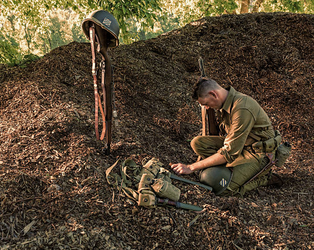 istock Soldier Prays While Holding Bible Over Death of Comrade 483709380