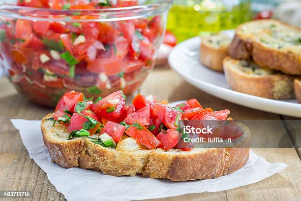 Bruschetta With Tomatoes Herbs And Oil On Garlic Cheese Bread Stock Photo - Download Image Now