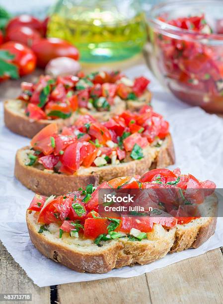 Bruschetta With Tomatoes Herbs And Oil On Garlic Cheese Bread Stock Photo - Download Image Now