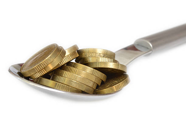 Spoon filled with gold coins stock photo