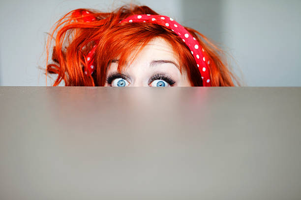 Funny girl hiding behind a table stock photo