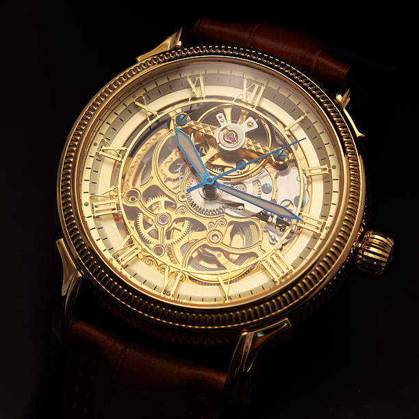 Golden wristwatch on black Golden wristwatch with a visible clockwork on black background. clockworks photos stock pictures, royalty-free photos & images