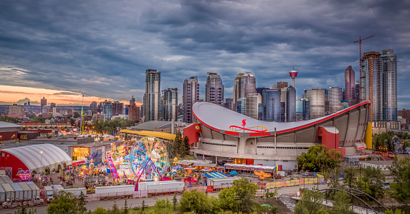 Calgary, Alberta, Canada - July 12, 2015: Calgary's skyline at night with the Scotiabank Saddledome. The dome with its unique saddle shape is home to the Calgary Flames NHL club, and is one of the oldest professional hockey arenas in North America. Calgary is also home to the famous and largest outdoor show in the world... the Calgary Stampede. A weeks worth of parades, rodeos, midways and professional performances from around the world.