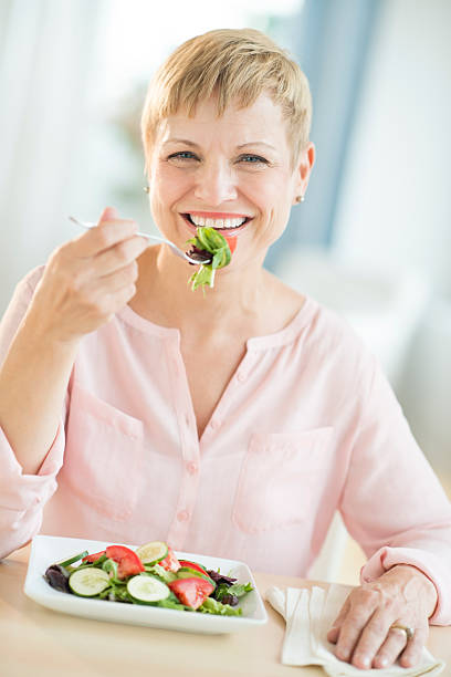 mulher feliz comer salada de legumes - dieting front view vertical lifestyles imagens e fotografias de stock