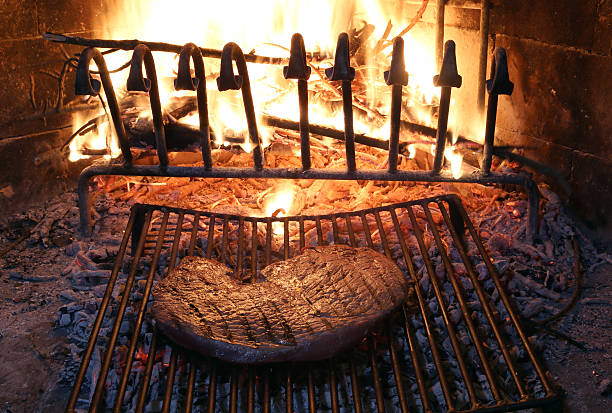 huge beef steak cooked on the barbeque fireplace with flame