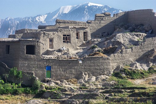 Tagab, Afghanistan - June 19, 2010: During a winter time, a traditional mud house overlooking mountain range in Afghanistan. This traditional house has been made with mud which is a good insulation material. All the windows are facing south side to gain the maximum amount of sunlight during the winters.