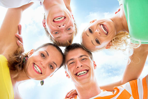 istock Group of happy young people in circle at beach 483722954