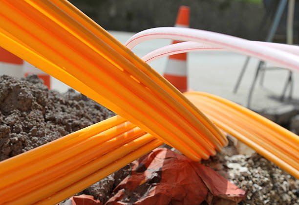 Orange pipes for fiber optics in a city road construction Many Orange pipes for fiber optics in a large city road construction to connect high speed internet digital subscriber line stock pictures, royalty-free photos & images