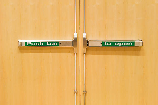 Emergency fire doors Close up of emergency fire doors, with sign "Push bar to open". door fire exit sign swinging doors fire door stock pictures, royalty-free photos & images