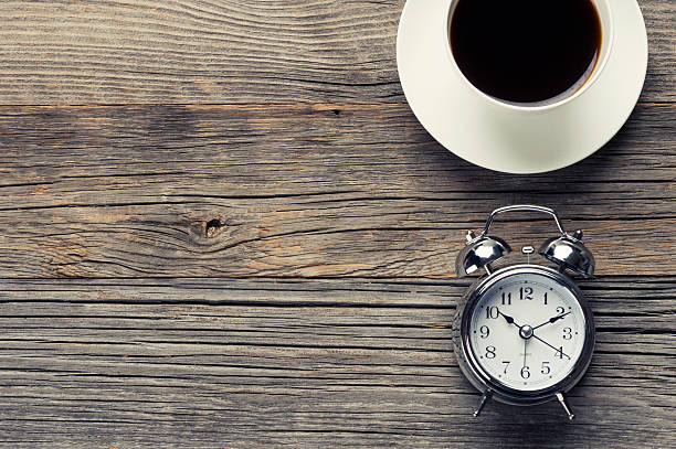 istock Clock and coffee on a wooden table. 483731098